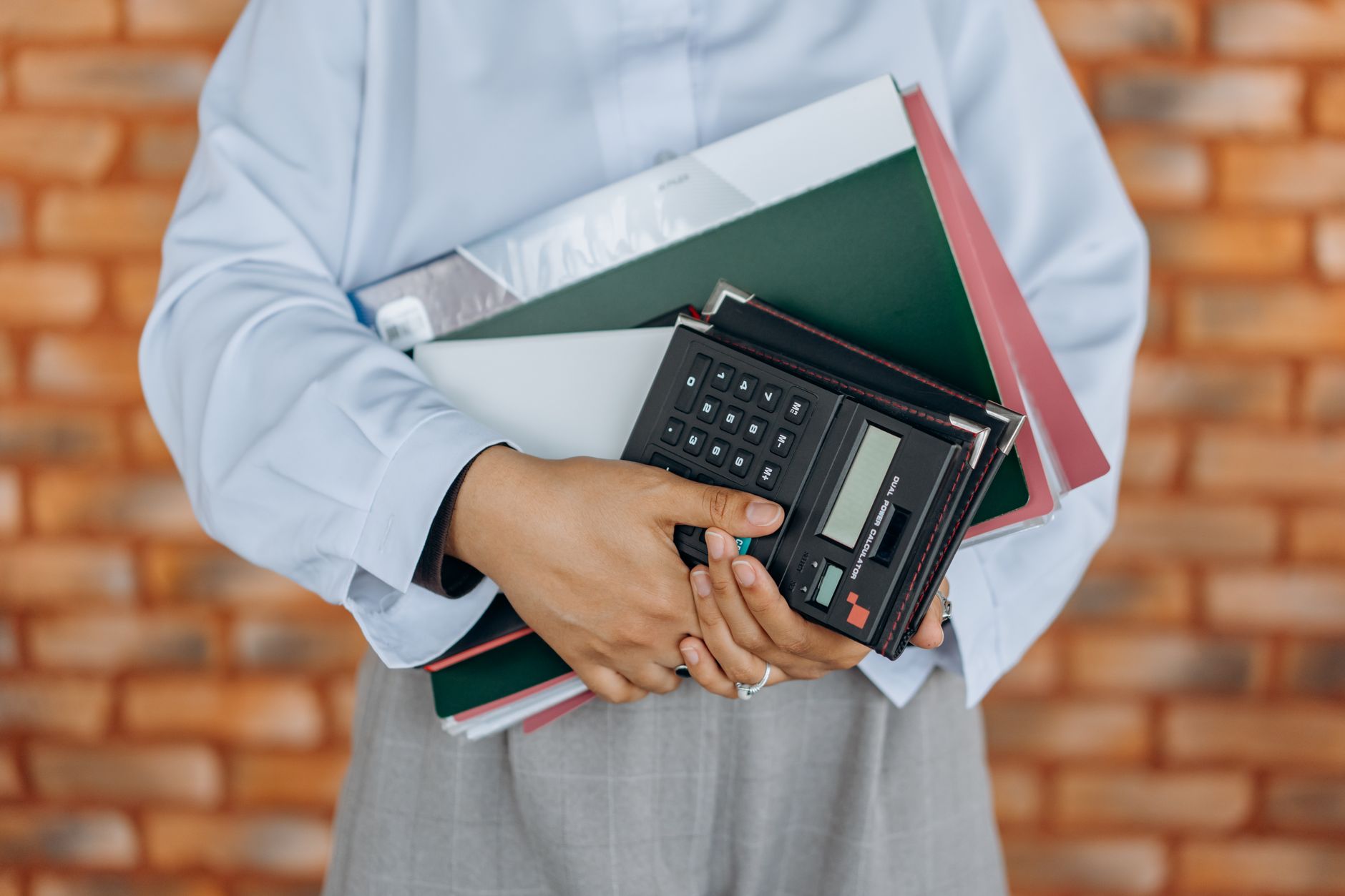 Profissional com calculadora e pastas de documentos.